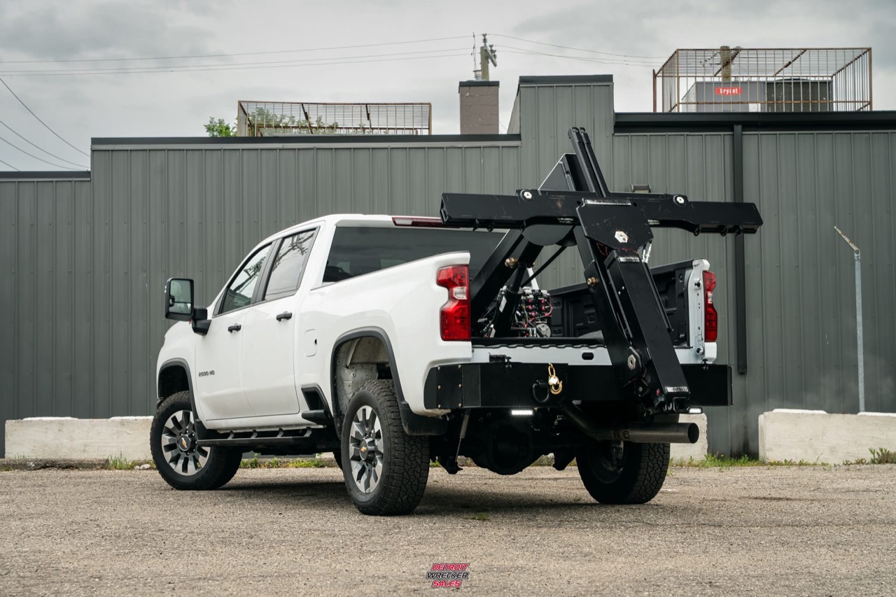 Baby Gladiator folded into its travel position on a white Chevrolet pickup.