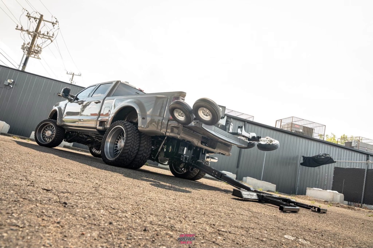 Gray Ford pickup with a Gladiator wheel lift extended behind the truck outside a workshop.