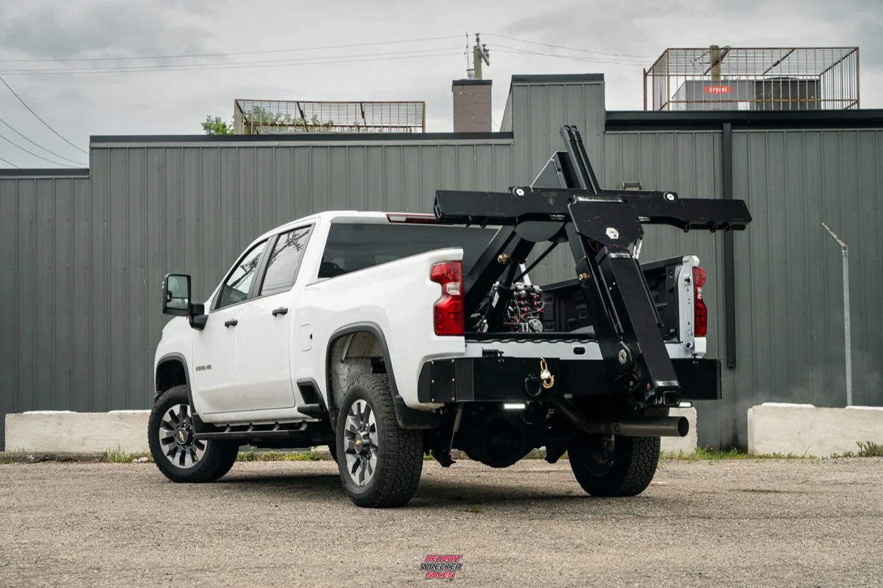 Baby Gladiator in-bed wheel lift stowed at the rear of a white Chevrolet pickup.