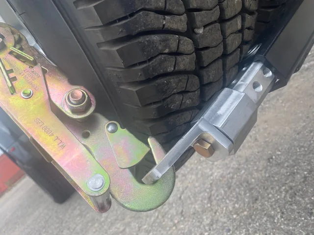 L-arm extender positioned beside a vehicle tire on a wheel lift.