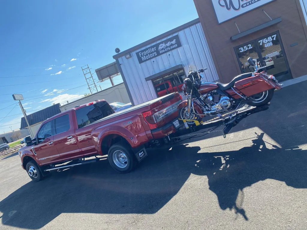 Side view of a red pickup carrying a motorcycle on the Lil Hercules attachment.